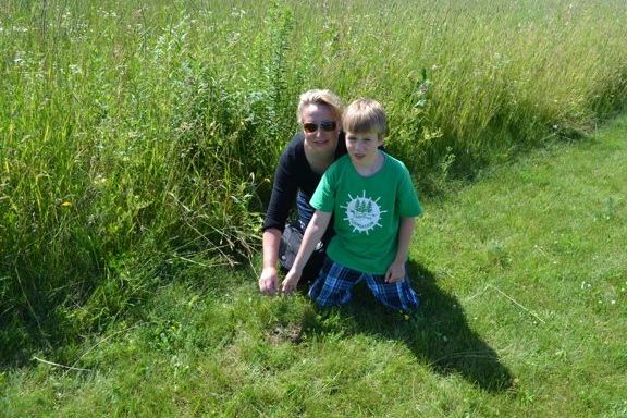 Executive Director Andrea Koehle Jones checks-up on seedlings planted by campers.