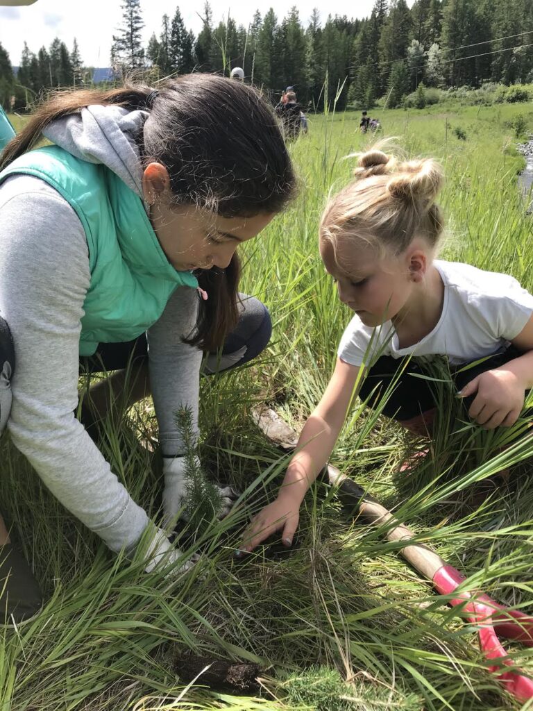 A child participating in hands-on tree planting and outdoor environmental education in nature.